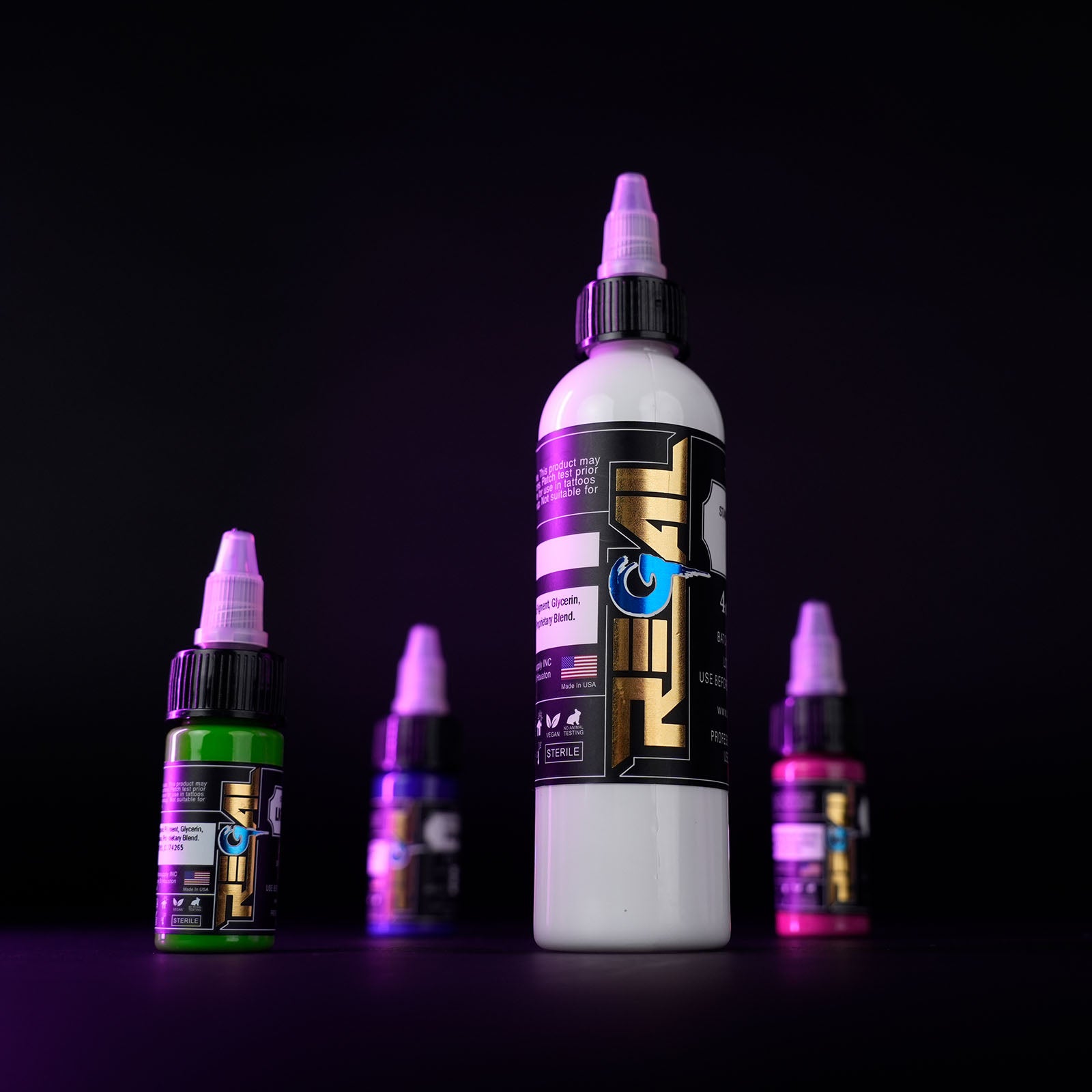 Regal tattoo ink bottles in multiple colors displayed on a dark studio background with purple lighting for professional tattoo artists.